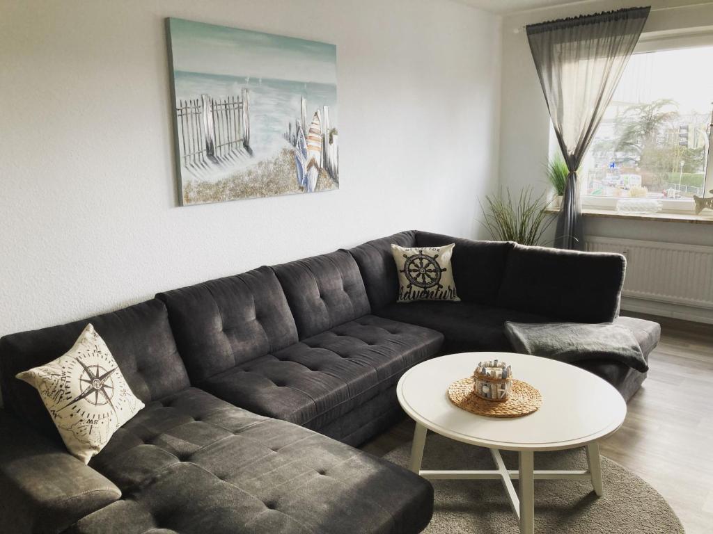 sala de estar con sofá negro y mesa en Küstenbude Sonne, en Grömitz