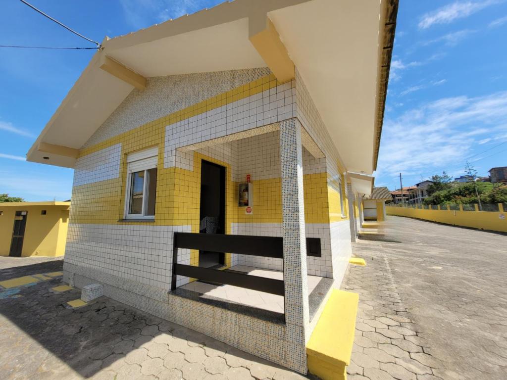 a small yellow and white building with a door at Pousada Genoveva - Apto com um dormitório in Farol de Santa Marta