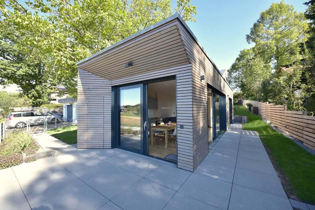 une petite maison avec des portes en verre sur le trottoir dans l'établissement Tinyhaus Adam, à Freiamt