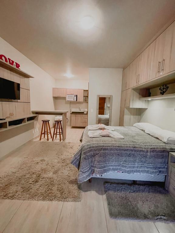 a bedroom with a bed and a kitchen with a table at Apartamento Girassol love in Monte Verde