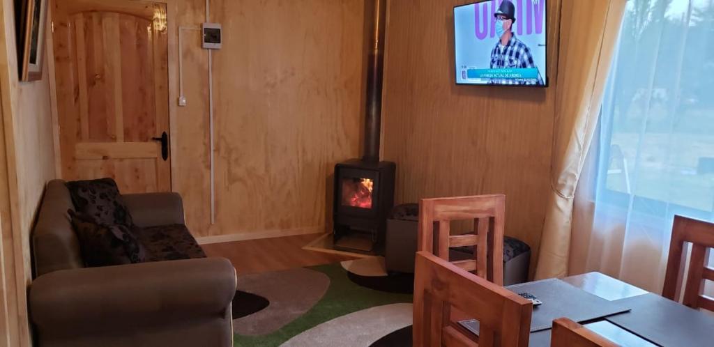 a living room with a fireplace and a stove at Cabañas P y R los canelos in Hornopiren