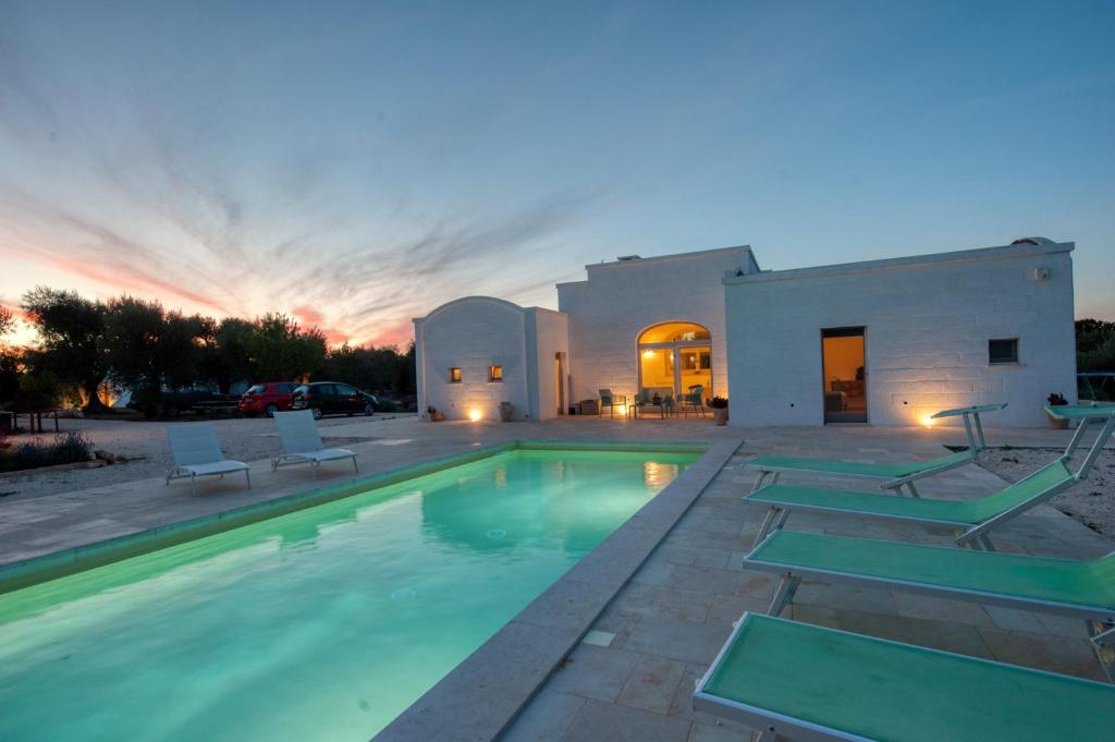 uma piscina em frente a uma casa com um pôr-do-sol em TRULLI ACQUASALA - Apulian Country Experience em Ostuni