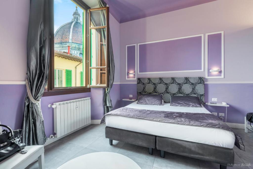 a bedroom with a bed with purple walls and a window at B&B Le Stanze del Duomo in Florence