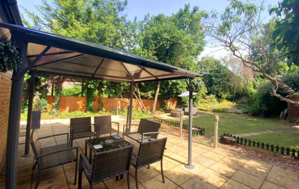 a patio with a table and chairs under an umbrella at Sleeplicity London Heathrow in Feltham