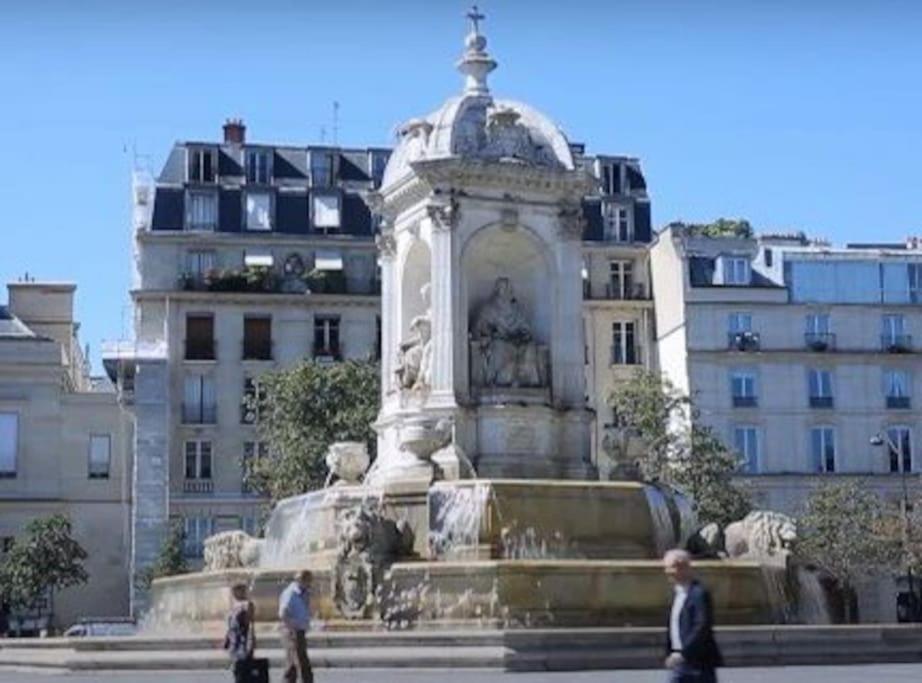 people walking around a fountain in front of a building at Studio Saint Germain des près in Paris