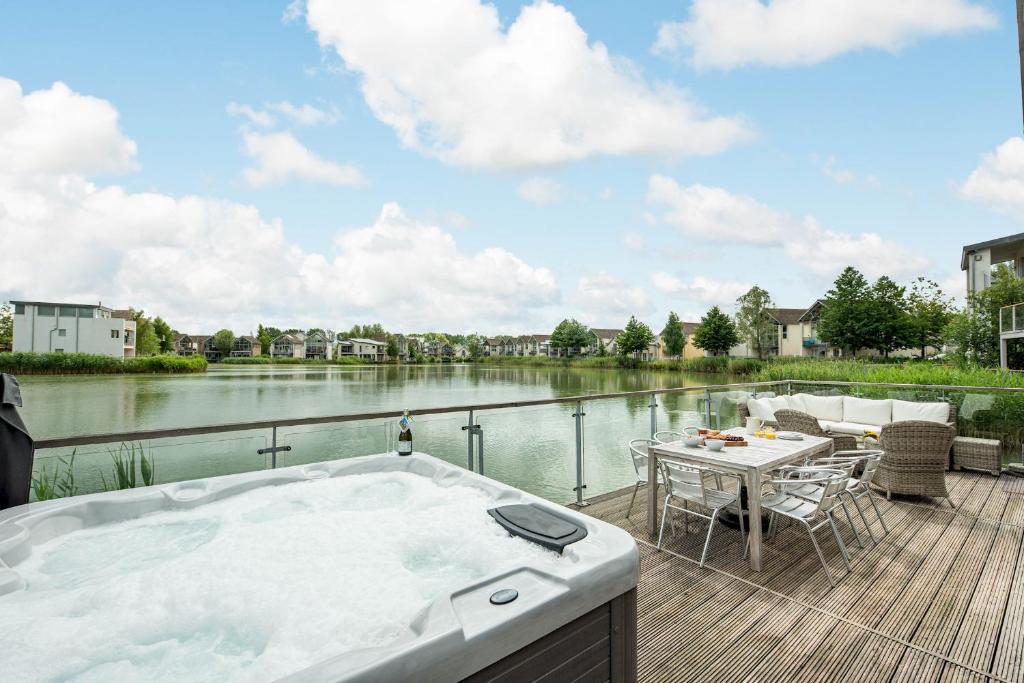 a bath tub sitting on a deck next to a river at Lakeside property with hot tub Barn Owl HM08 in Somerford Keynes