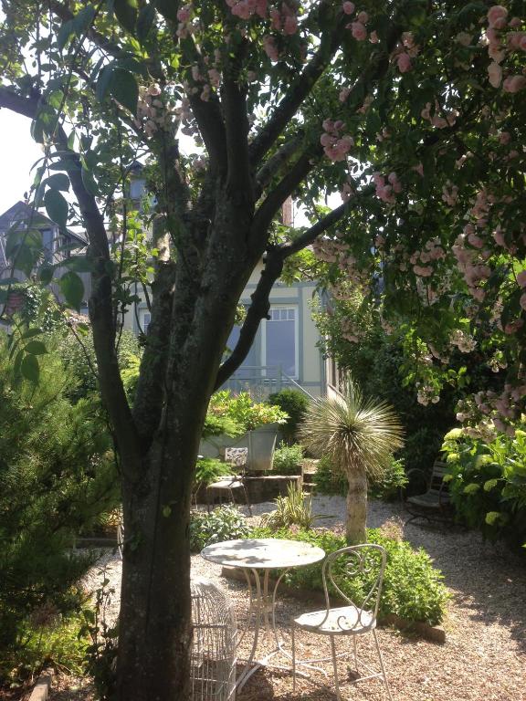 a table and chairs under a tree in a garden at Logis Saint-Léonard in Honfleur