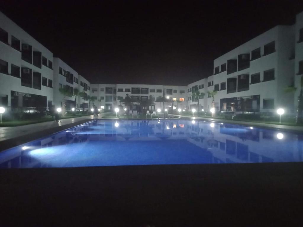 ein großer Pool vor einigen Gebäuden in der Nacht in der Unterkunft MAGIC HOUSE in Mansouria