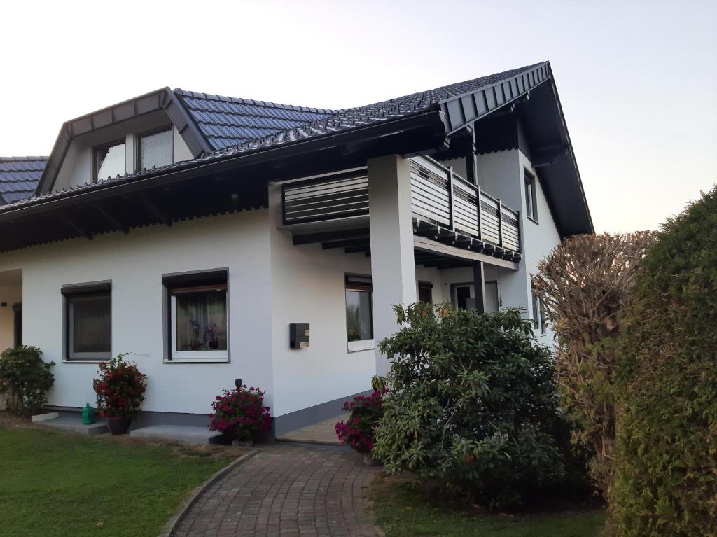 ein weißes Haus mit einem Balkon und einer Auffahrt in der Unterkunft Ferienwohnung Annemarie in Sankt Kanzian am Klopeiner See