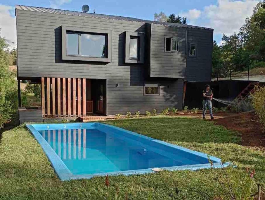 una casa con piscina frente a ella en Casa Condominio Pucon Villarrica, en Molco