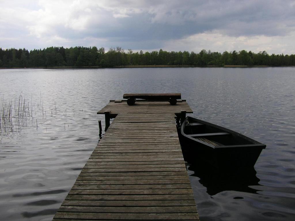 a wooden dock with a boat on a lake at Domek Letniskowy - Jerutki in Jerutki