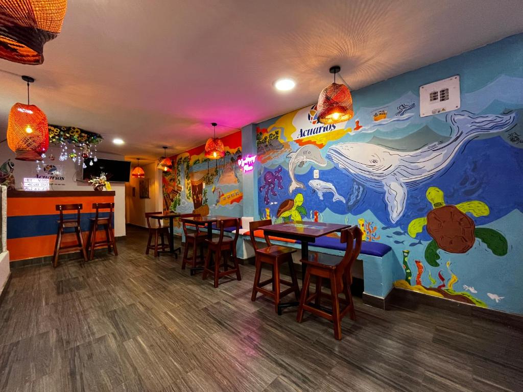 un restaurante con mesas y sillas y un mural en Acuarios Hostal, en Playa Ladrilleros