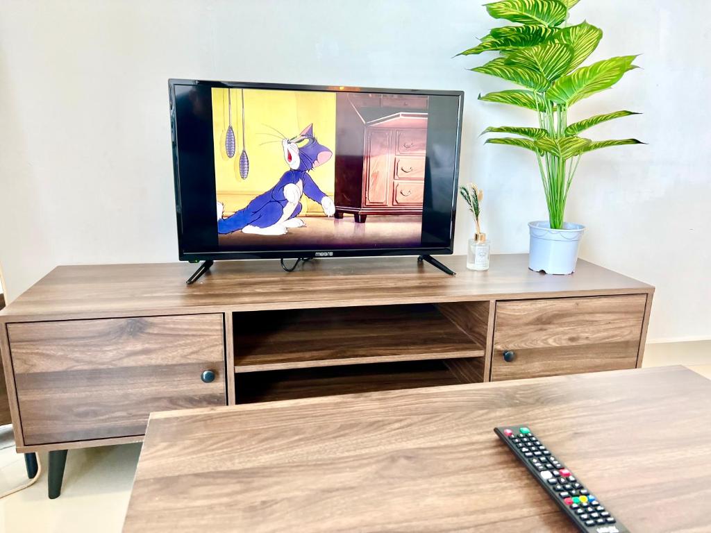 a tv sitting on top of a wooden entertainment center at H 1-5 pax Cozy house 3 Bed Trefoil Setia Alam Wifi and TV SCCC in Shah Alam
