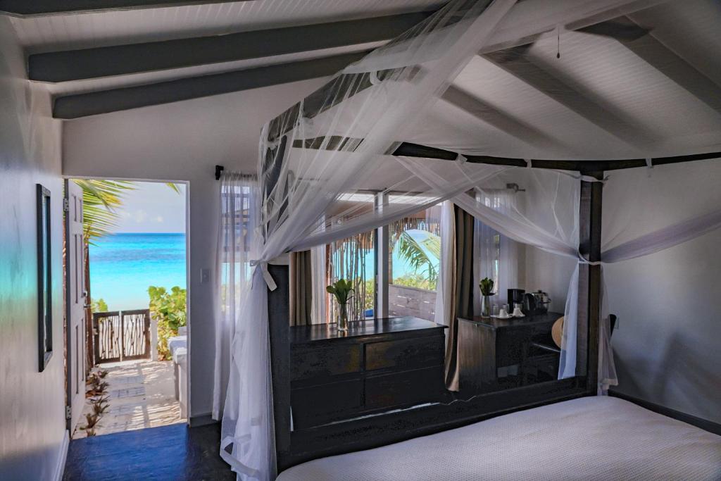 una camera con letto a baldacchino e vista sull'oceano di Conch Beach Cabins 