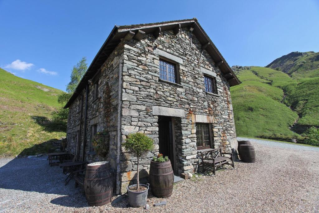 a small stone building with barrels in front of it at The Mountain Cottages - Carpenters in Coniston