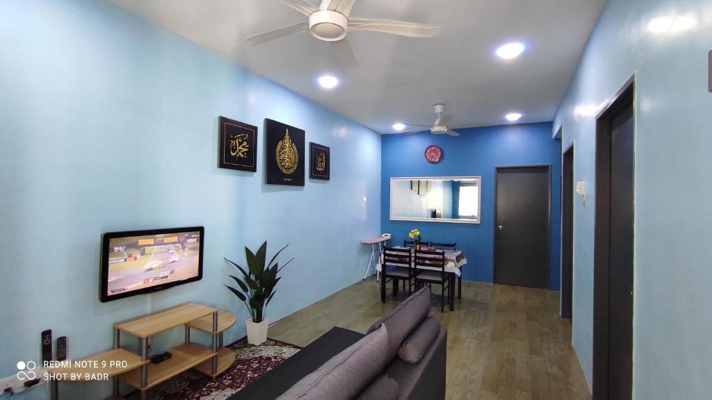 Ain's Homestay في كانجار: غرفة معيشة بجدران زرقاء وأريكة وطاولة