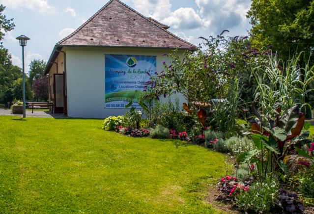 un jardín con una señal en el lateral de un edificio en Camping municipal de la Lande, en Nexon