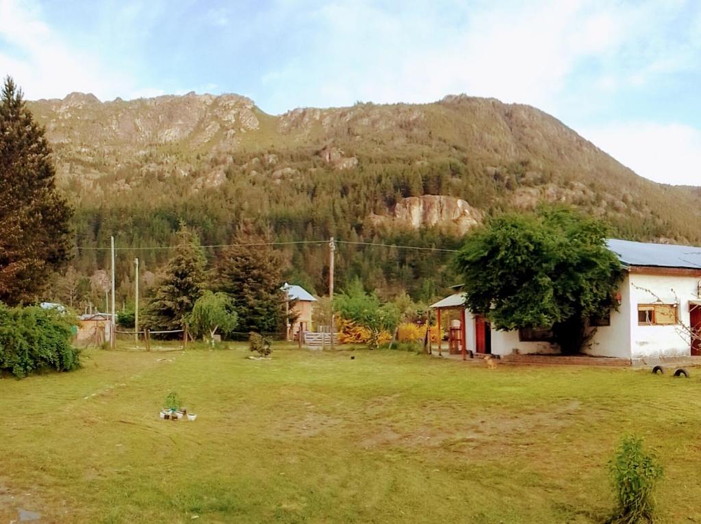 una casa en un campo con una montaña en el fondo en Habitación compartida en vivienda familiar en Lago Puelo