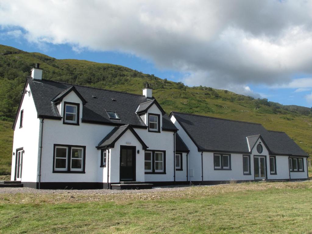 a white house with a hill in the background at Watercolour in Ardgour