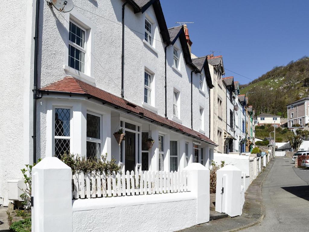 a row of white houses with a white picket fence at Llwynon Cottage in Llandudno