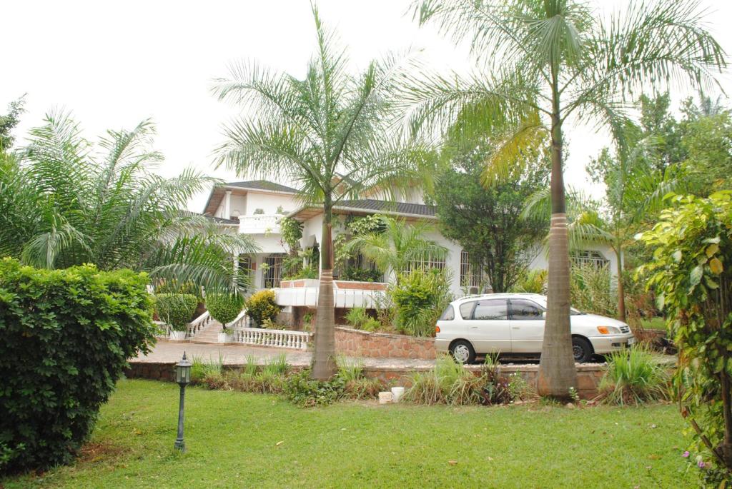 a white car parked in front of a house with palm trees at Kiriri Residence Hotel in Bujumbura