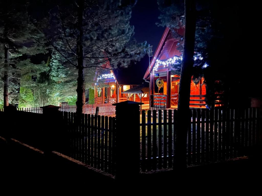 uma casa iluminada à noite com uma cerca em Orzechowy Zakątek em Zbiczno