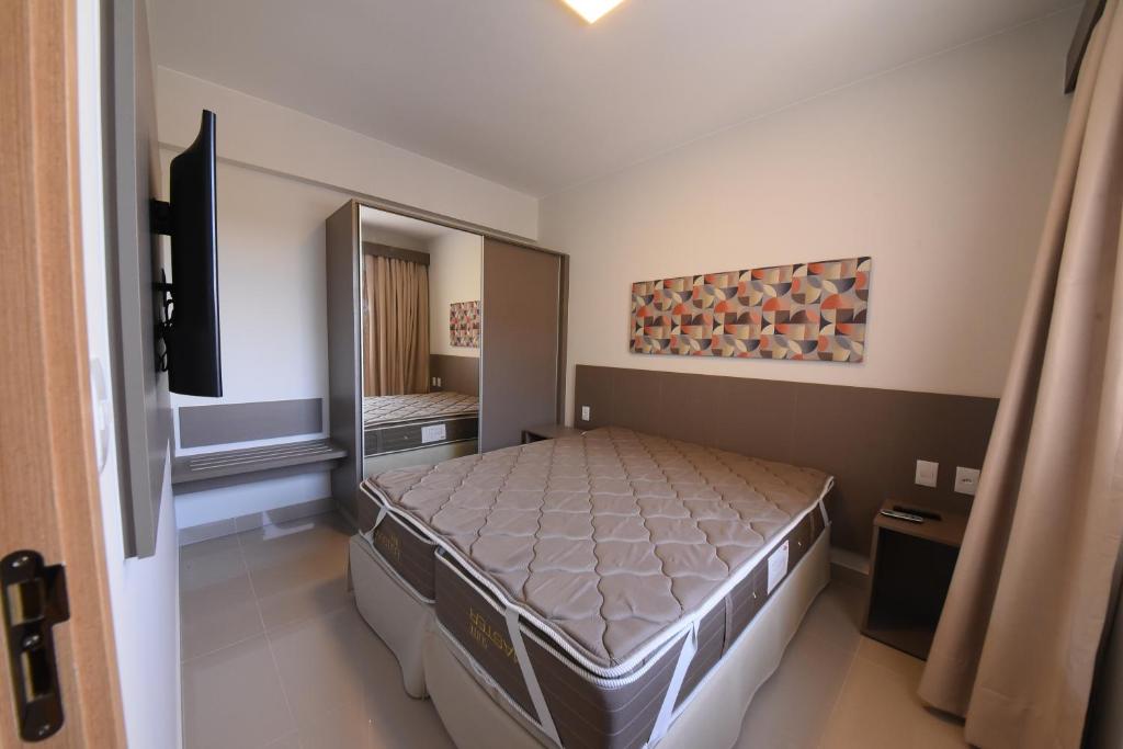 Park Veredas Resort في ريو كوينتي: غرفة نوم بسرير ومرآة كبيرة