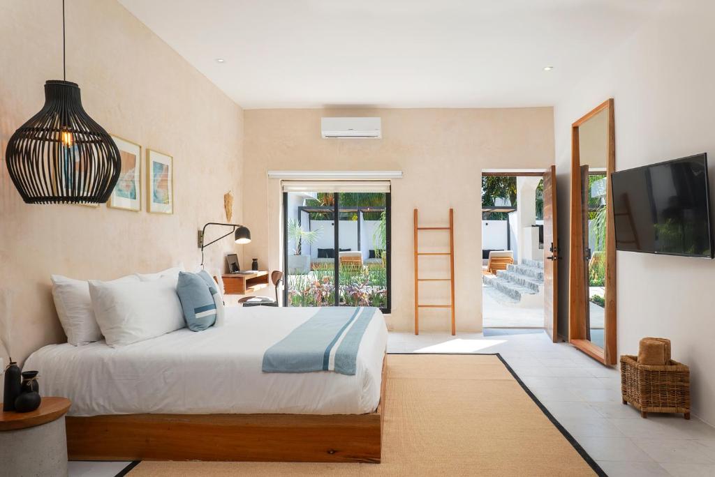 - une chambre avec un lit et une porte coulissante en verre dans l'établissement Illa Cozumel, à Cozumel