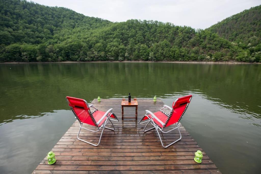 Bălana的住宿－Casa de pe Lac，湖上码头上的三把椅子和一张桌子