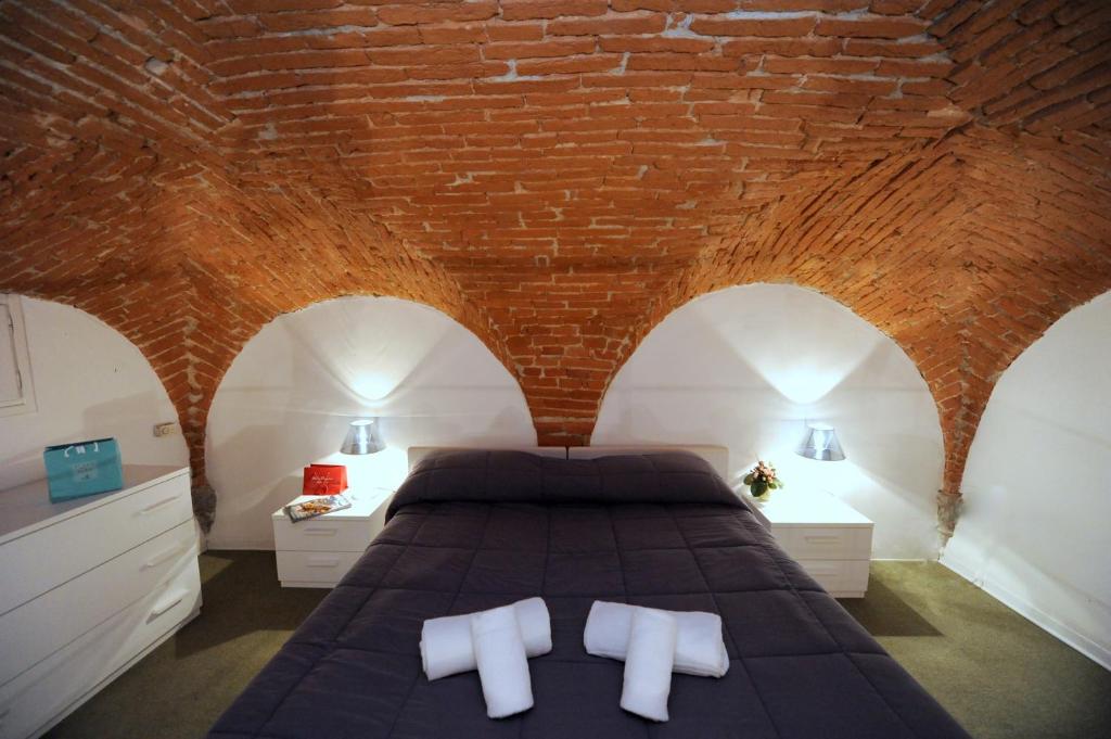 1 dormitorio con cama y pared de ladrillo en Acacia Firenze - Gelsomino, en Florencia