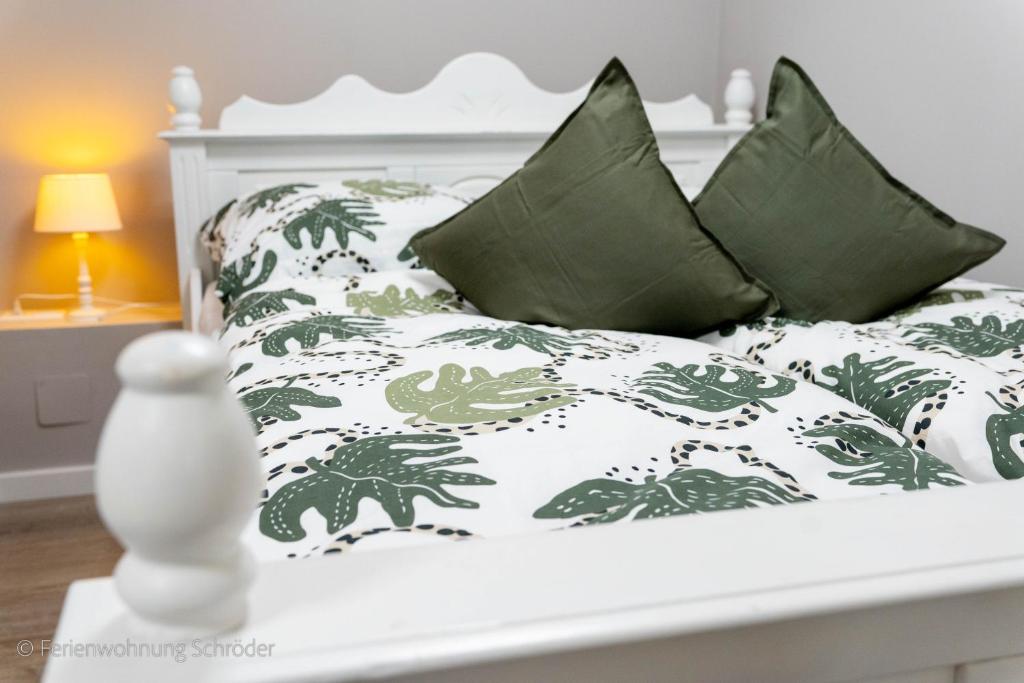 a white bed with green and white sheets and pillows at Ferienwohnung Schröder in Barntrup