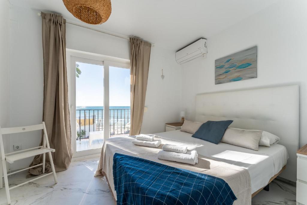 sypialnia z łóżkiem i dużym oknem w obiekcie Sea Front Beach House Macarena C w mieście Sitio de Calahonda