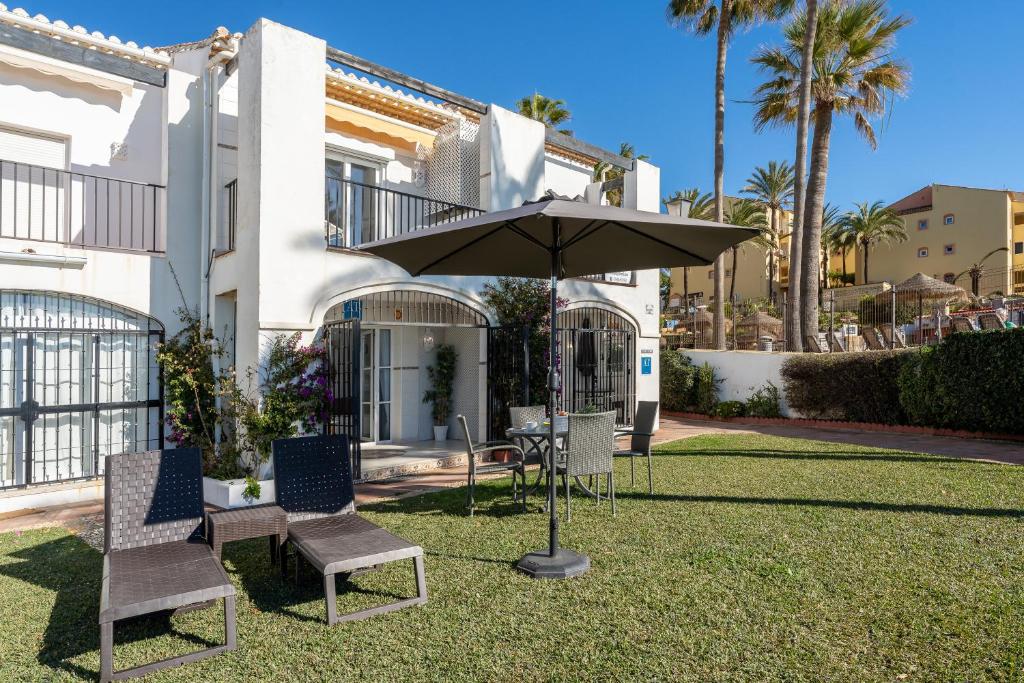 stół, krzesła i parasol przed domem w obiekcie Sea Front Beach House Macarena C w mieście Sitio de Calahonda