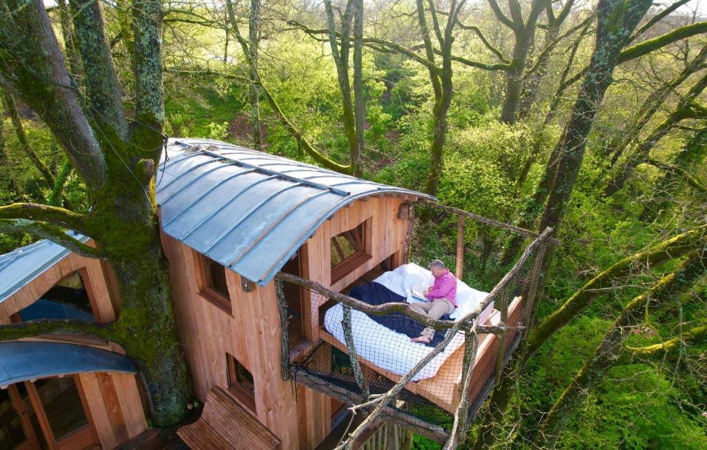 a woman in a tree house in the woods at Cabane perchée - Les Cabanes de Fallot - sauna bain-froid piscine in LʼIsle-Bouzon