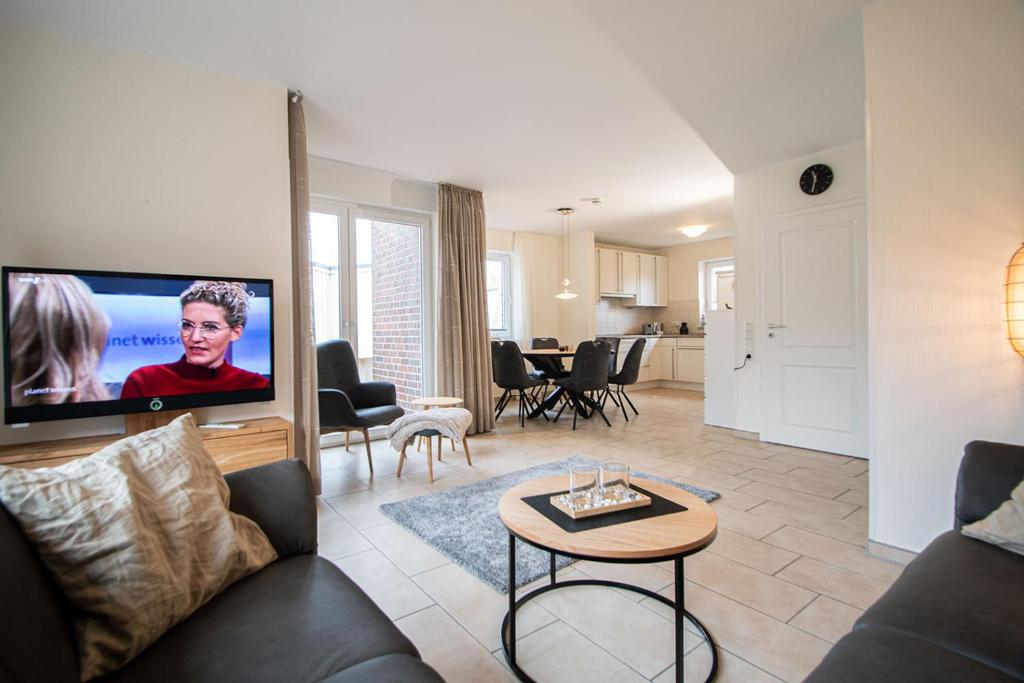 een woonkamer met een bank en een flatscreen-tv bij Ferienhaus Auszeit in Borkum