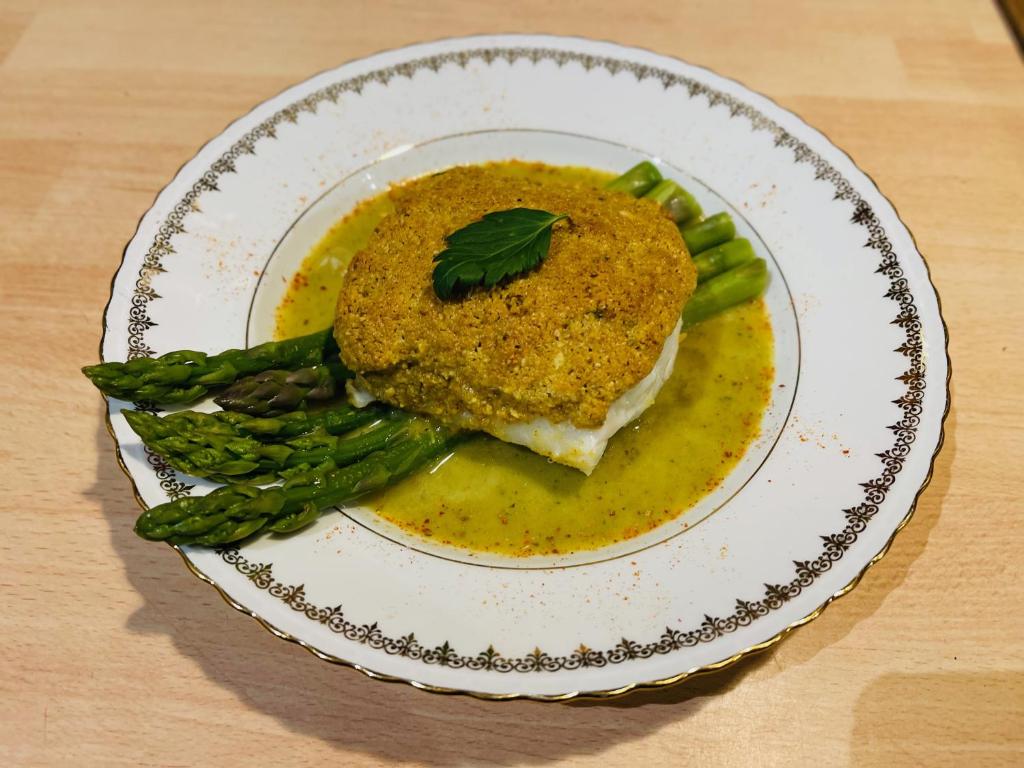 a plate of food with a piece of meat and asparagus at Maison LGBT des Monts Bleus in Saint-Roman-de-Tousque