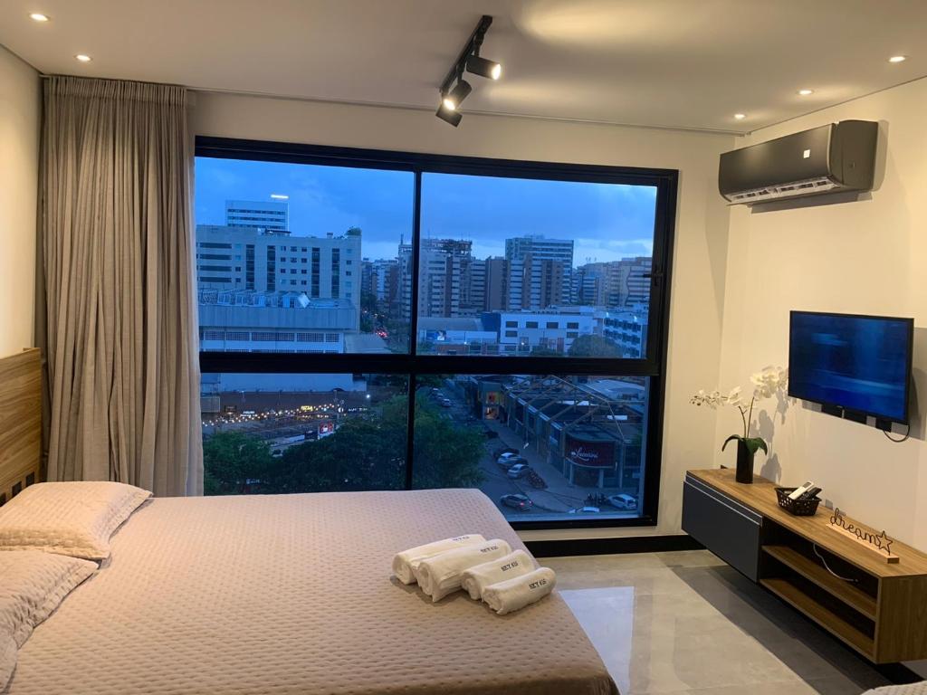 Dormitorio con ventana grande, cama y TV en Sky Concept 816, en Maceió