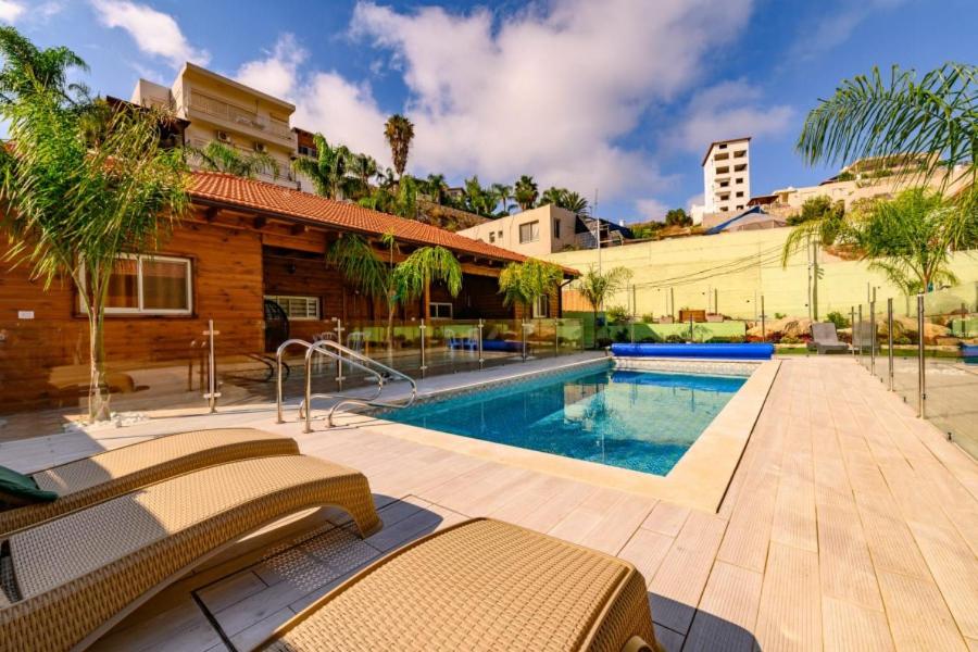 a house with a swimming pool in a yard at צמרת הצימרים - מתחם צימרים מקסים עם בריכה במתחם וג'קוזי פרטי - Vacation complex with heated pool and private jacuzzi in Dāliyat el Karmil