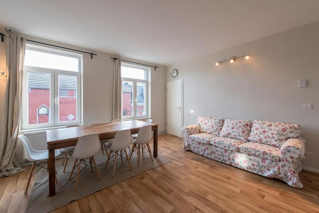 uma sala de estar com uma mesa e um sofá em Appartement 4 chambres à Liège em Liège