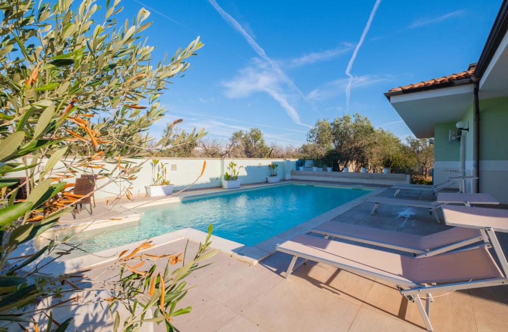 a swimming pool with two lounge chairs and a house at Villa Vimade con Piscina Privata in Marina di Mancaversa