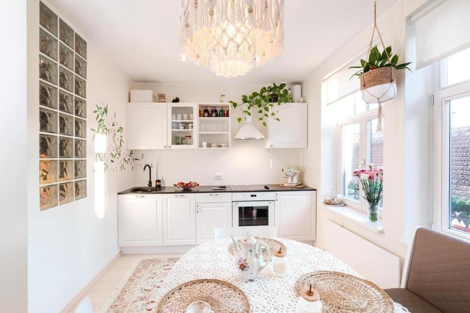 a white kitchen with a table and a chandelier at Rüütli 24-2 in Pärnu