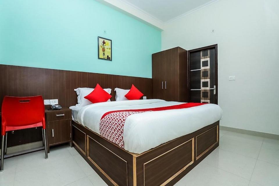 1 dormitorio con 1 cama grande y 1 silla roja en Hotel Imperial, en Greater Noida