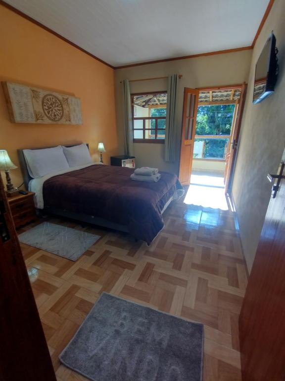 - une chambre avec un lit et une porte coulissante en verre dans l'établissement Chalés de Santana, à Tiradentes
