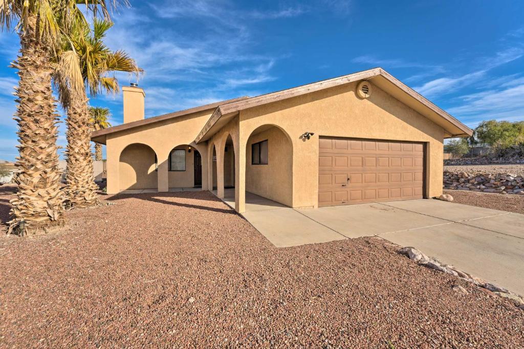 a house with a garage and a palm tree at Bullhead City Home Less Than 2 Mi to Colorado River! in Bullhead City