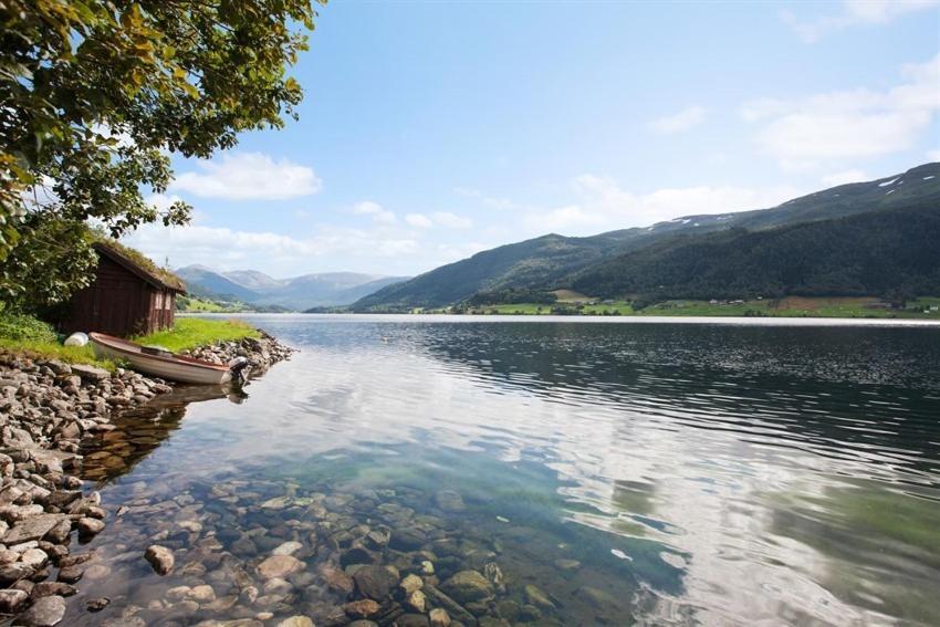 a lake with a house and a boat in the water at Voss- Myrkdalen Lodge in Vossestrand