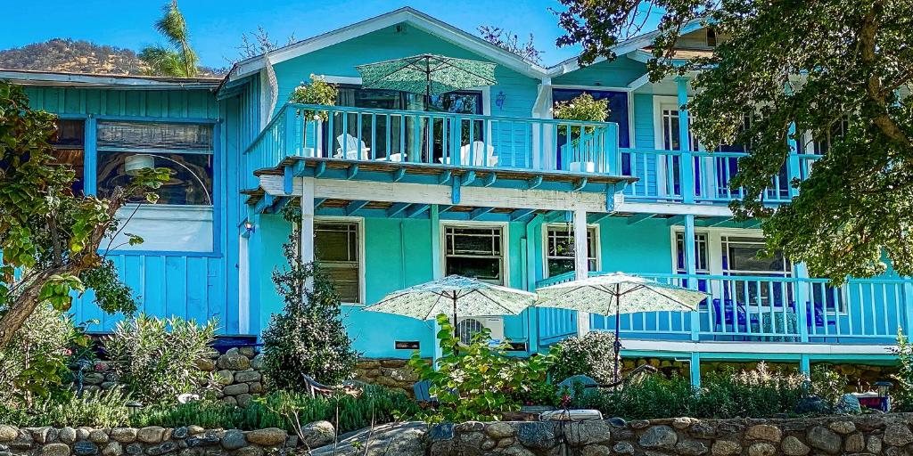 una casa azul con sombrillas delante en Rio Sierra Riverhouse en Three Rivers