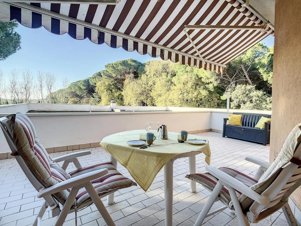 een patio met een tafel en stoelen op een balkon bij Residence il Pino in Marina di Castagneto Carducci