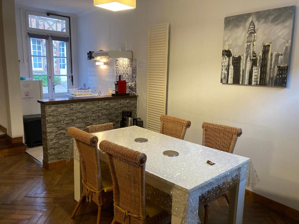 a kitchen with a table with chairs and a counter at Le Logis de Pélagie in Neufchâtel-en-Bray