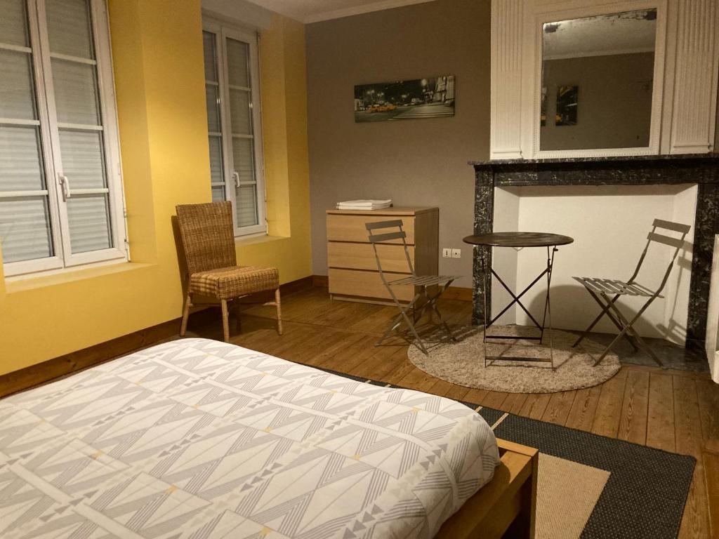 a bedroom with a bed and a table and chairs at Le Logis de Pélagie in Neufchâtel-en-Bray