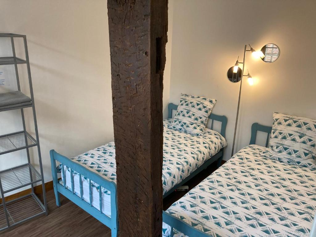 a bedroom with two twin beds and a ladder at Le Logis de Pélagie in Neufchâtel-en-Bray